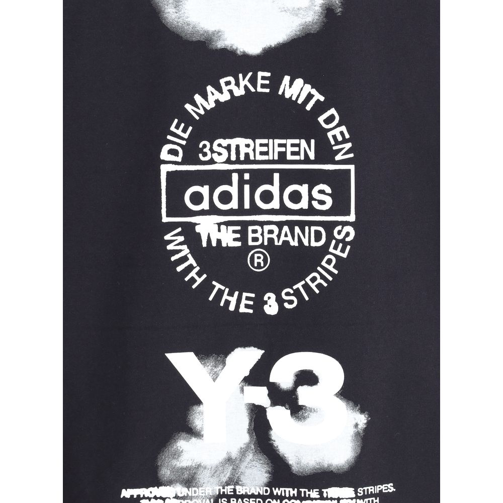 Close-up of Y-3 T-Shirt maxi print with Adidas logo and text in white. High-contrast graphic detail on premium black men's T-shirt.