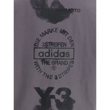 Close-up of Y-3 T-Shirt with maxi print highlighting Adidas logo, Yohji Yamamoto text, and artistic black graphic details on gray fabric.