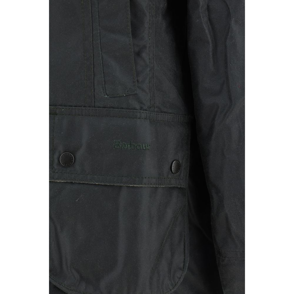 Close-up of Barbour Breadnell waxed Jacket pocket detailing with embossed Barbour logo and snap-button closure in green waxed cotton.
