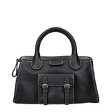 Front view of Chloé black leather handbag featuring dual buckle flap pocket and white stitching, stylish choice for women's designer bags.
