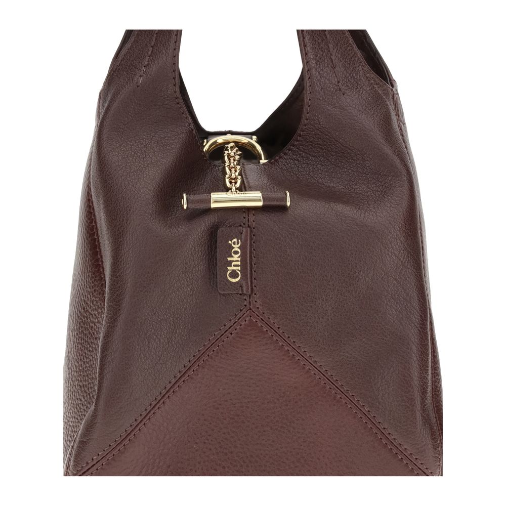 Close-up of Chloé Small Balloon Shoulder Bag featuring gold-tone bar closure with engraved logo and fine leather stitching detail.