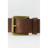 Close-up of Hugo Boss brown leather belt showing antique brass buckle engraved with BOSS logo, stylish men's accessory.